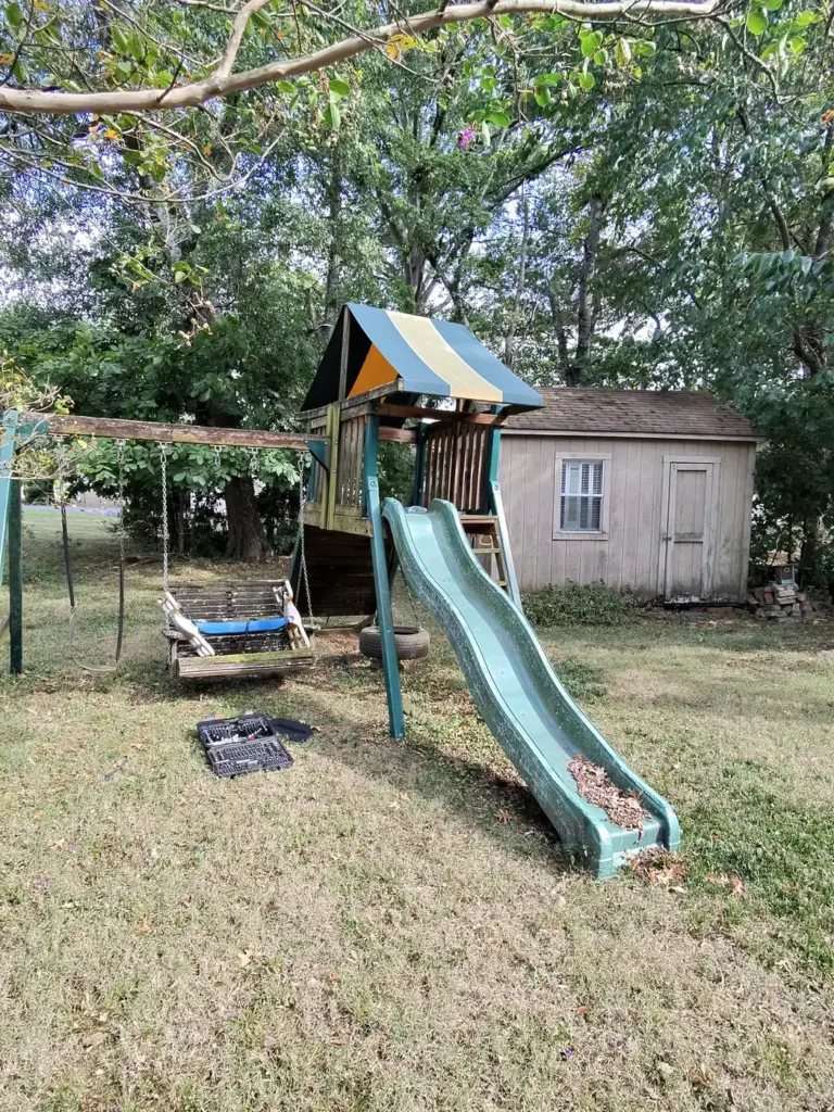Old wooden backyard playset and shed ready for removal