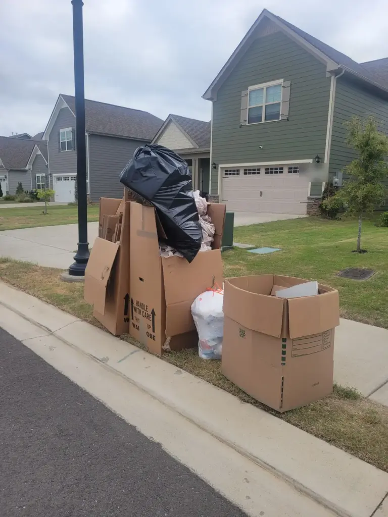 Curbside pile of moving boxes and trash bags ready for household junk pickup