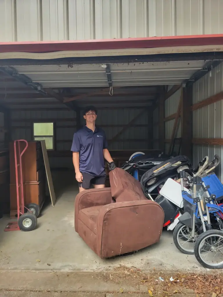 BoroBoys crew member hauling an old recliner, dresser and strollers out of a storage building