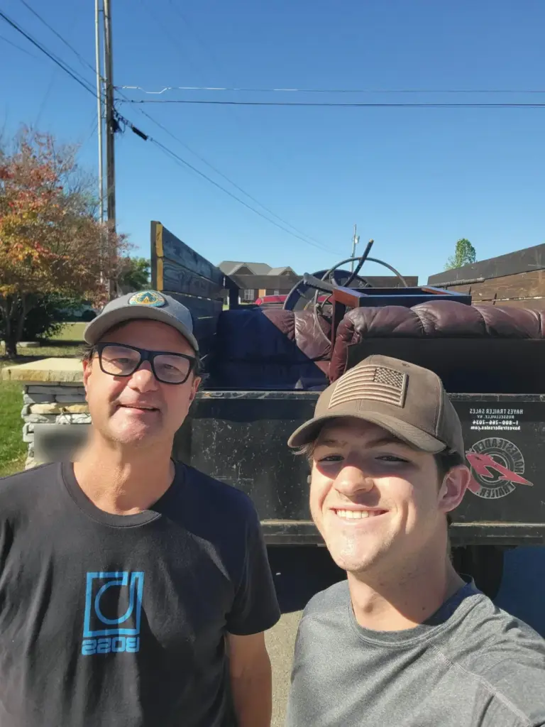 BoroBoys crew member with a happy customer beside a trailer loaded with old recliners in Murfreesboro TN