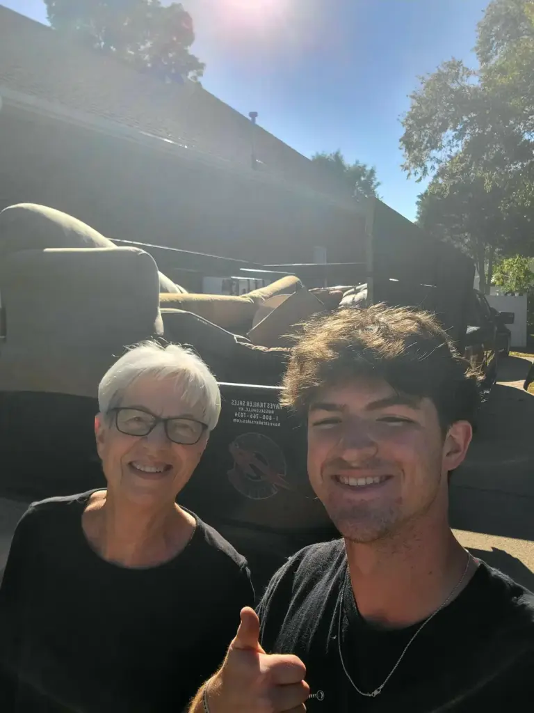 Happy customer with a BoroBoys crew member in front of a trailer loaded with old furniture