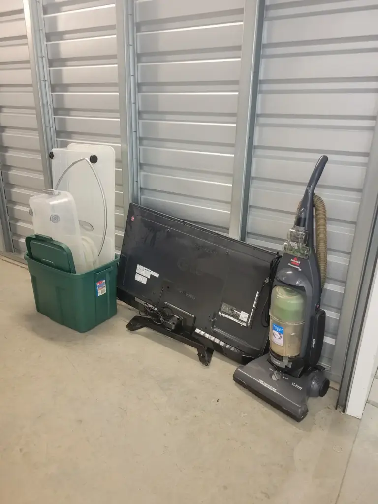 Old TV, vacuum and storage bins ready for pickup during a storage unit cleanout